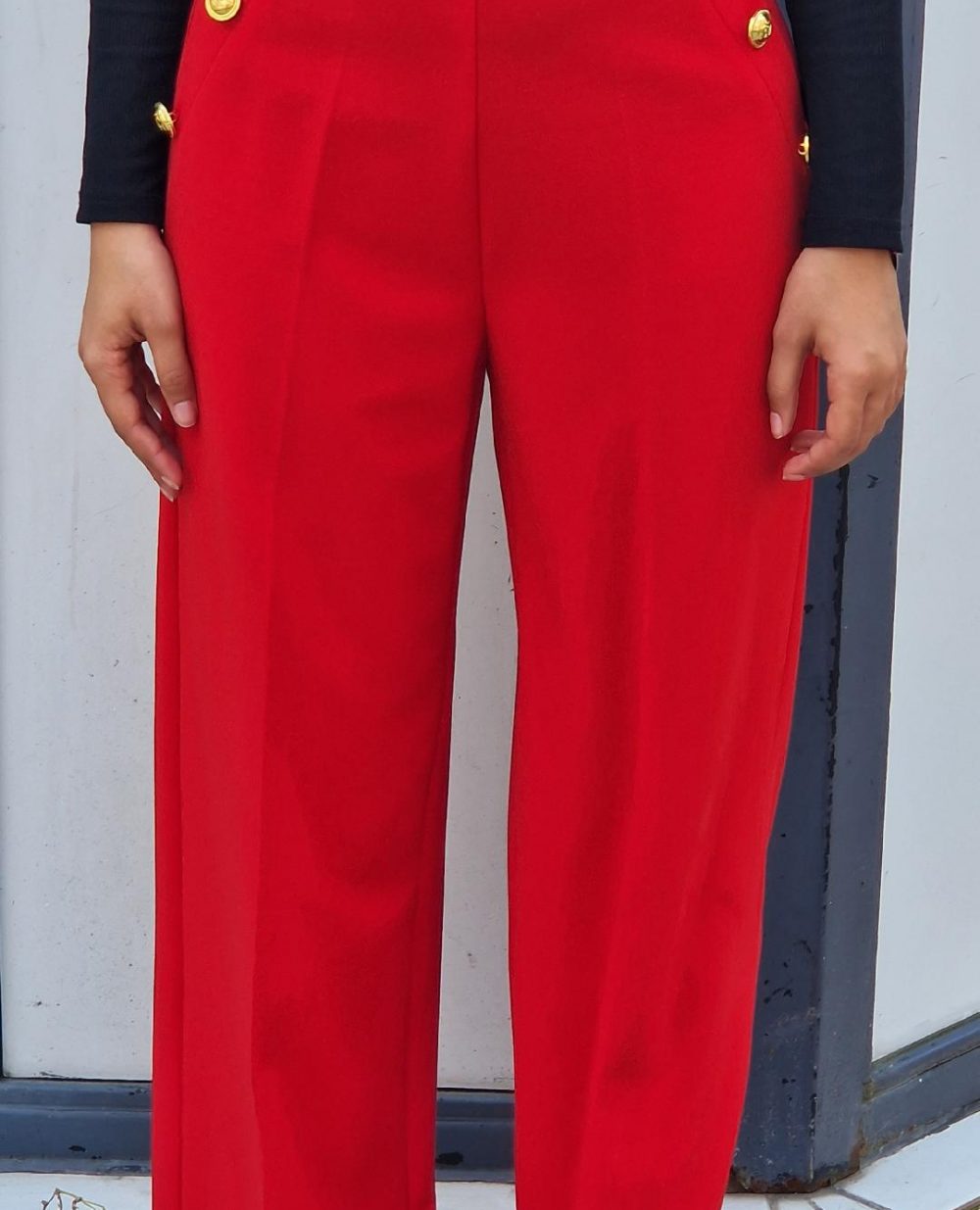 Pantalon à pince rouge vif. Possède des boutons avec motif ancre sur les fausses poches sur le côté.